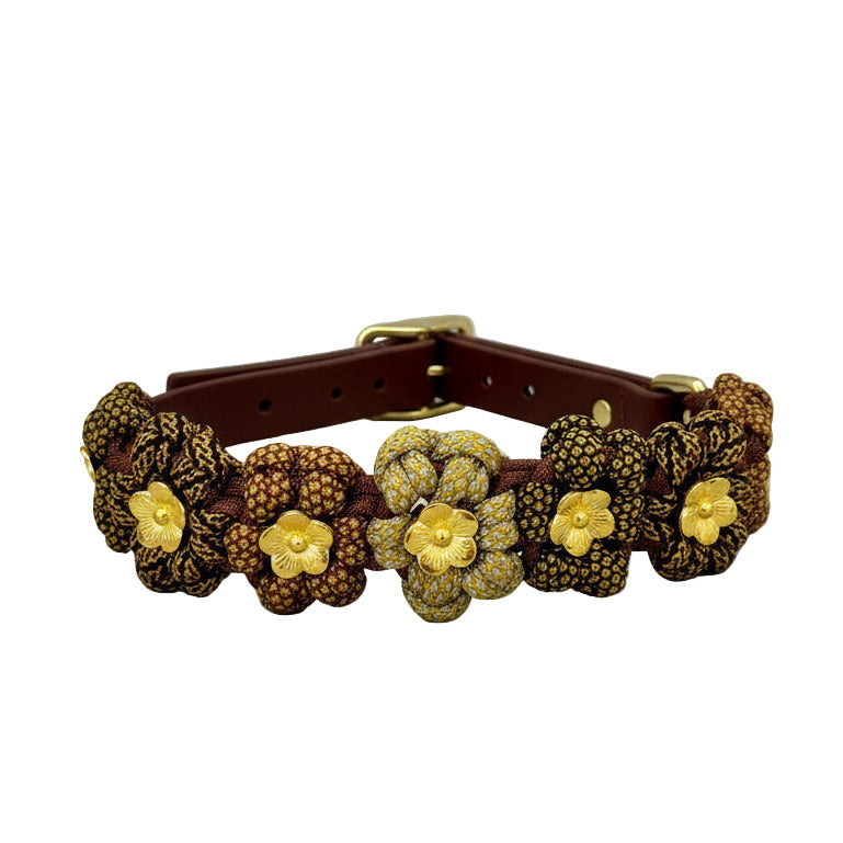 Brown leather collar with gold floral decorations on a light gray background